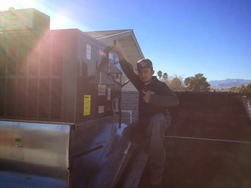 HVAC technician performing Boiler Repair on a rooftop unit in Youngsville